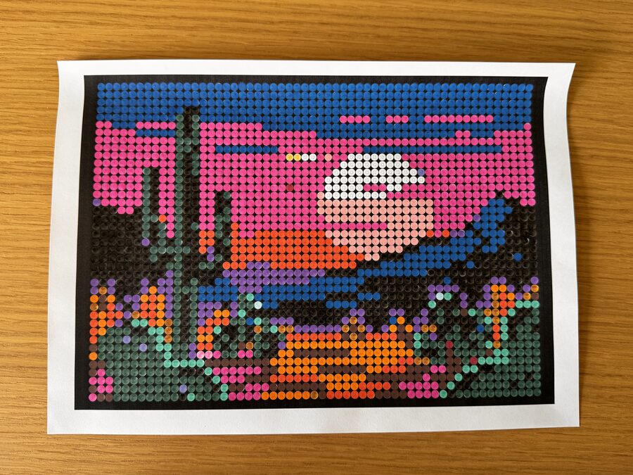 Ingekleurde versie van een woestijn-zonsondergang met cactus en flamingo in NOVI's colour-by-letter formaat — roze hemel boven oranje horizon